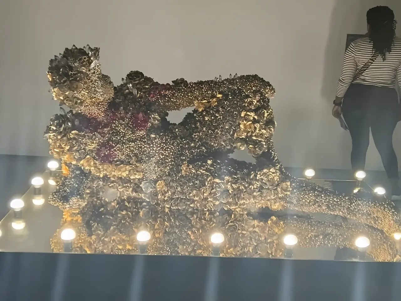 A richly textured metallic artwork illuminated in the gallery