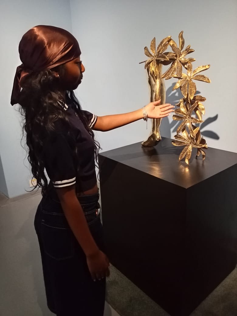 A visitor engaging closely with a golden botanical sculpture