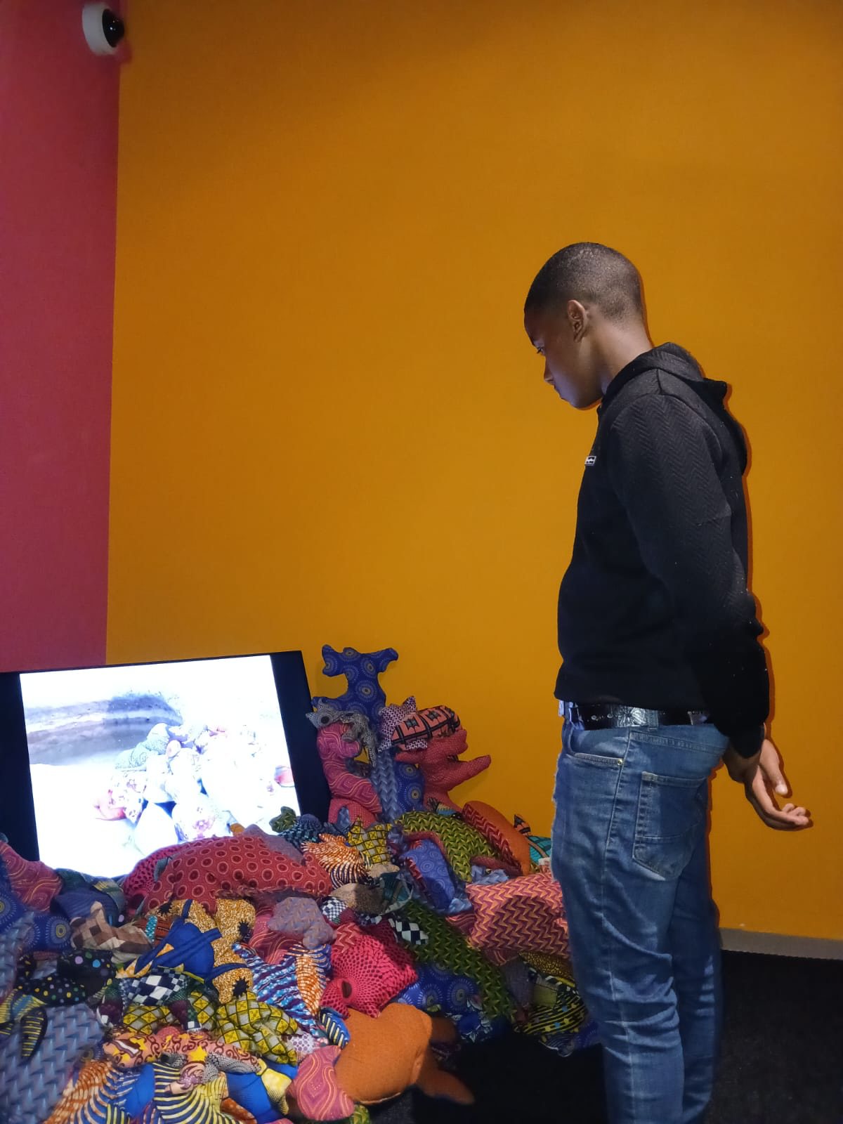 A visitor studying a vibrant mixed-media installation
