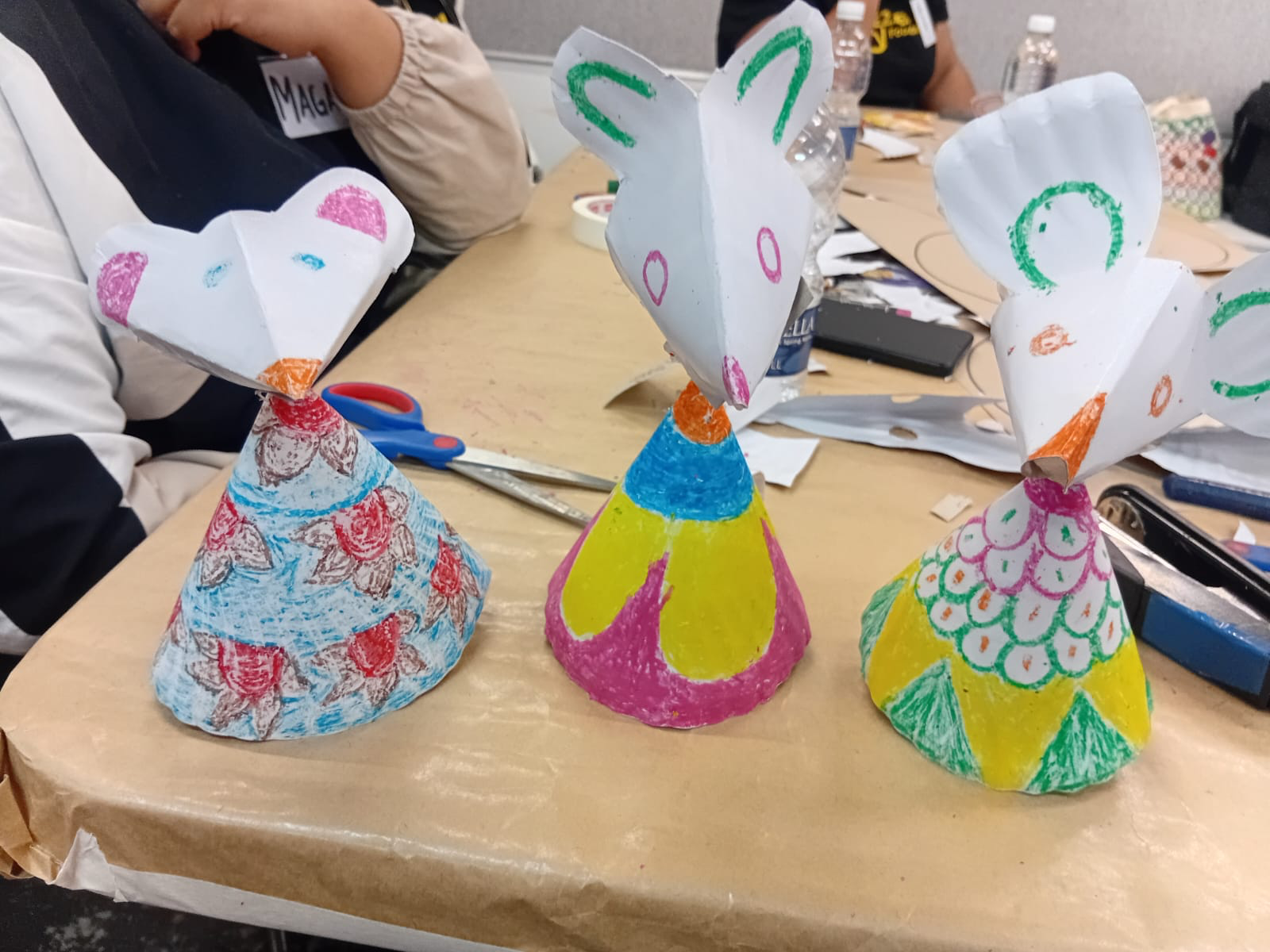 Three colourful handmade paper mice on the volunteer workshop table