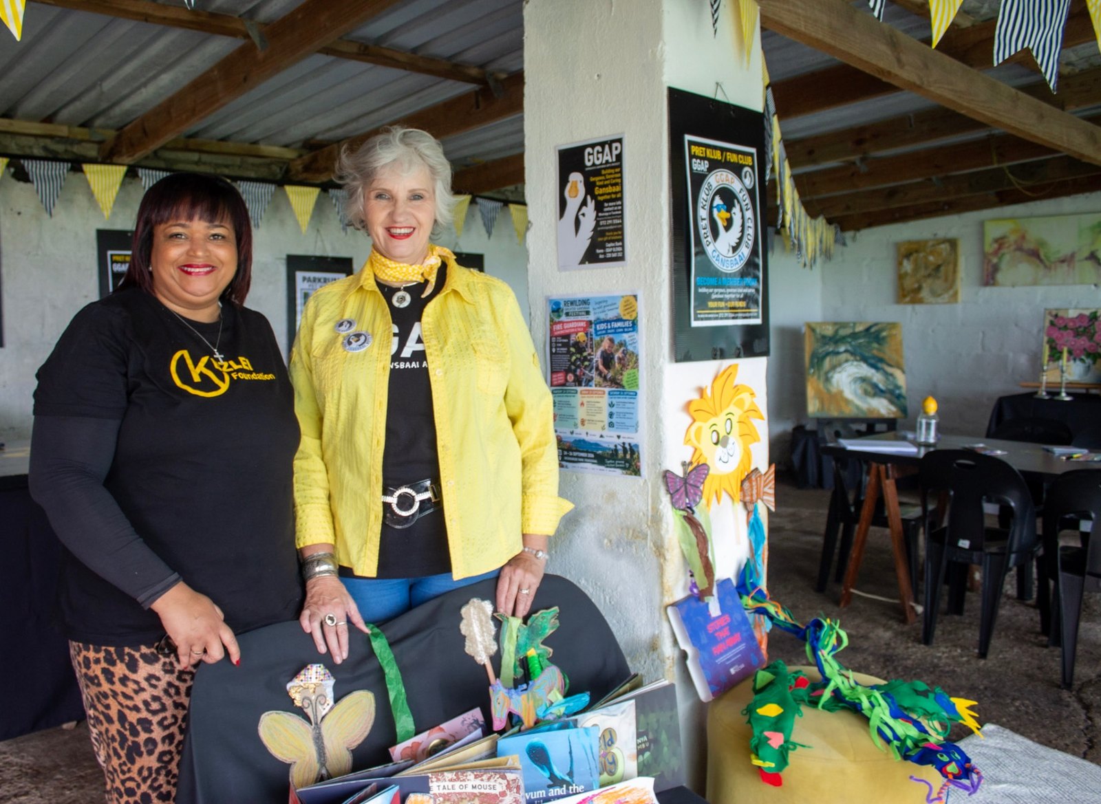 Chantal with a Gorgeous Gansbaai Arts Project host beside storybooks and handmade characters