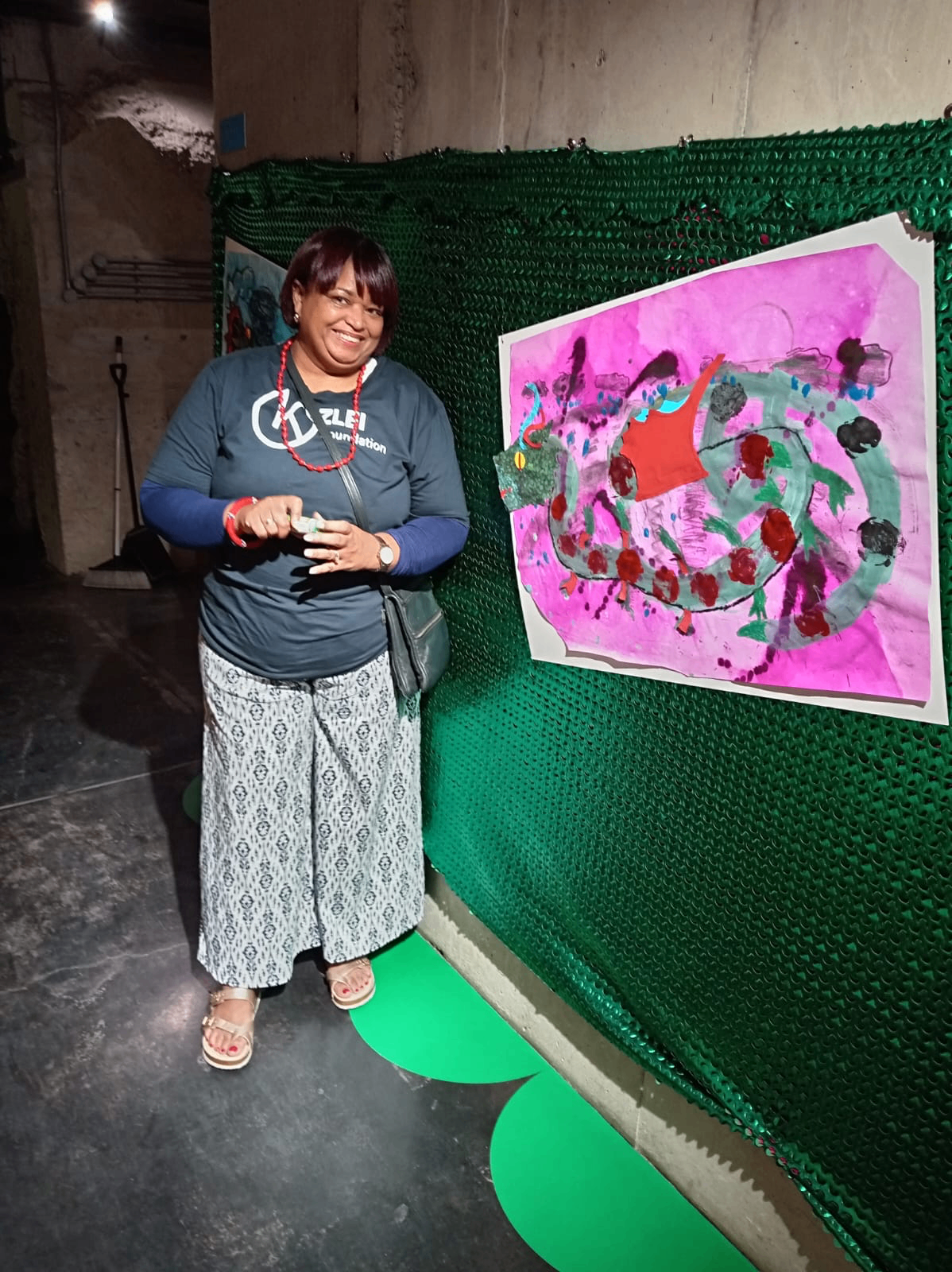 Kezlei Foundation team member alongside a learner's painted artwork
